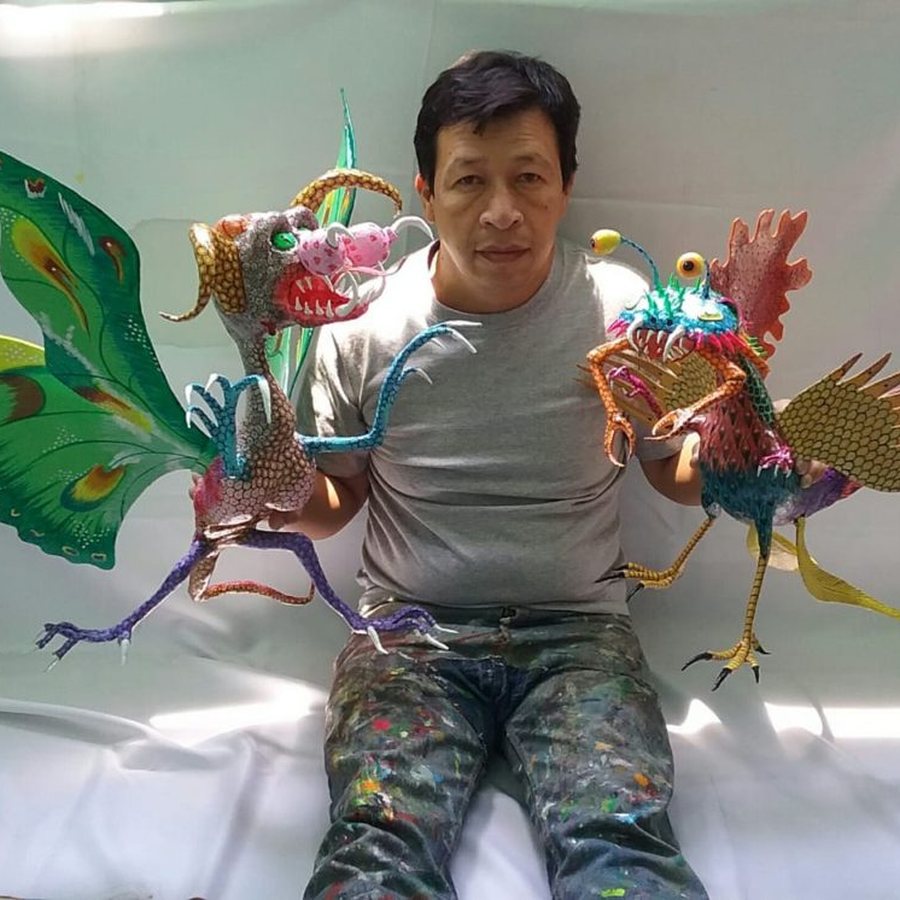 Artesano de la familia Linares sosteniendo dos alebrijes