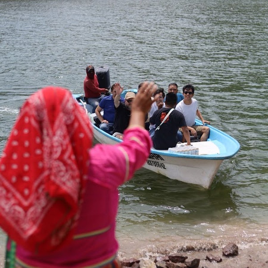 Una mujer wixárika recibe con la mano a una panga de viajeros que llega a la orilla